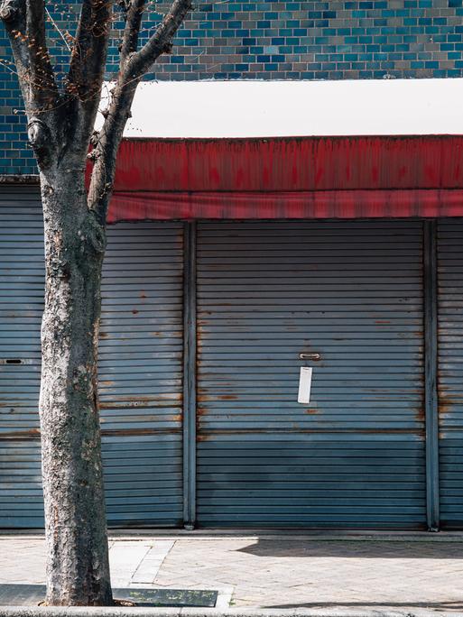 Außenansicht eines Gebäudes in Japan. Ein Metallgitter ist heruntergelassen. Das Gebäude sieht verlassen aus. 