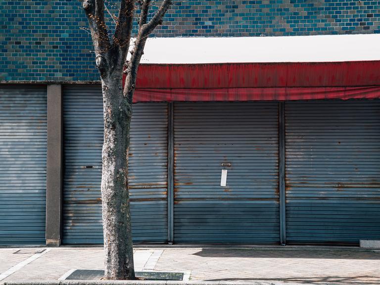 Außenansicht eines Gebäudes in Japan. Ein Metallgitter ist heruntergelassen. Das Gebäude sieht verlassen aus. 