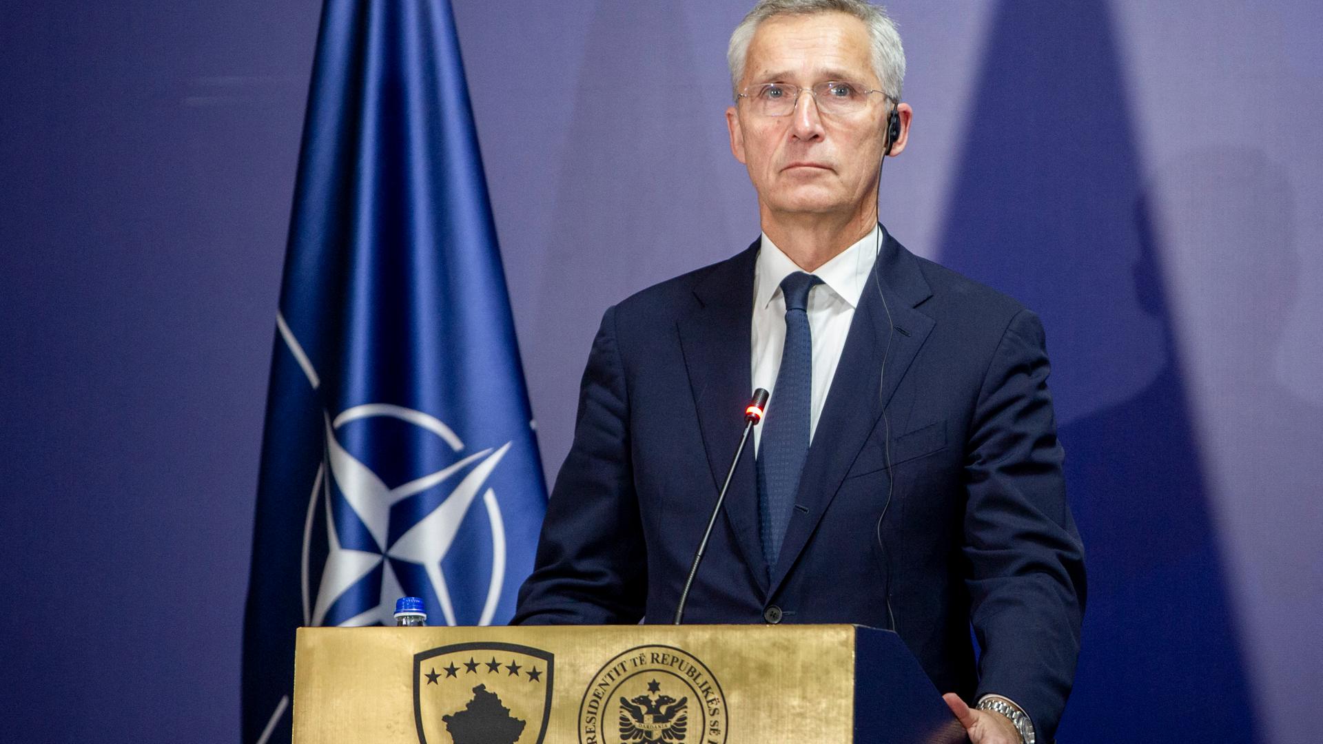 Stoltenberg steht neben einer NATO-Flagge hinter einem Rednerpult.