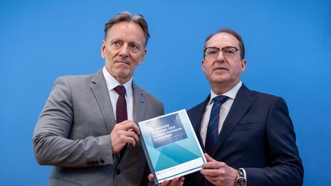 Die beiden stehen nebeneinander vor der blauen Wand der Bundespressekonferenz und halten gemeinsam den Lagebericht.