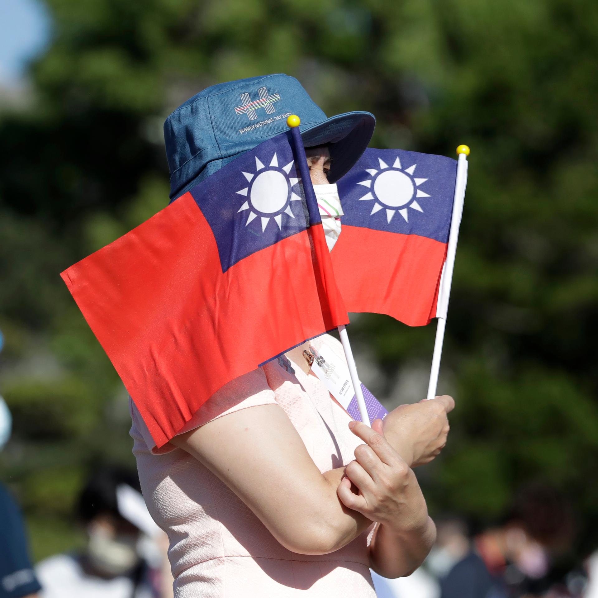 Eine Frau hält zwei taiwanesische Flaggen