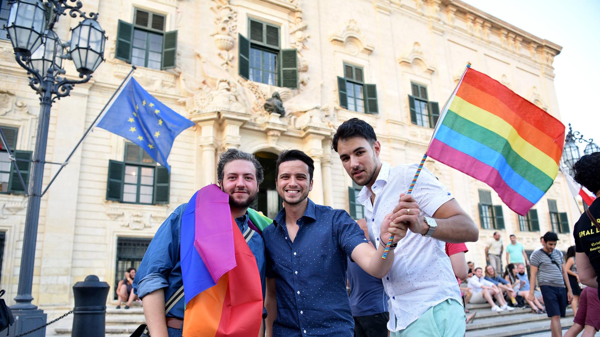 Menschen feiern die Einführung der gleichgeschlechtlichen Ehe in Malta 2017 und schwenken eine Regenbogenfahne.