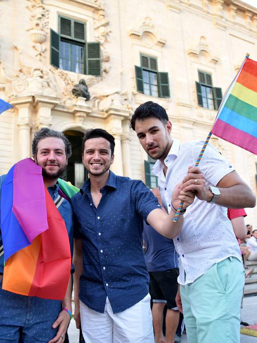 Menschen feiern die Einführung der gleichgeschlechtlichen Ehe in Malta 2017 und schwenken eine Regenbogenfahne.