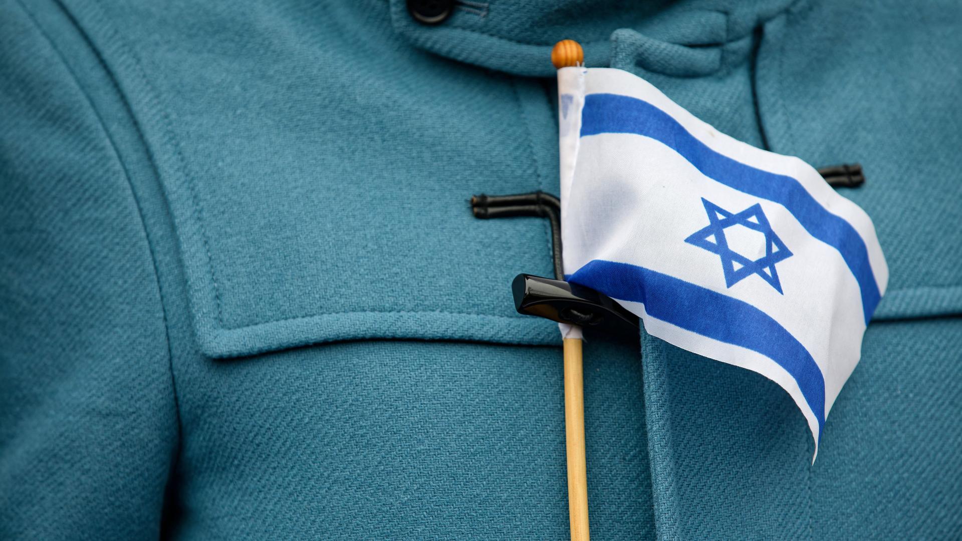 Nahaufname einer kleinen israelischen Flagge an der Knopfleiste eines Mantels