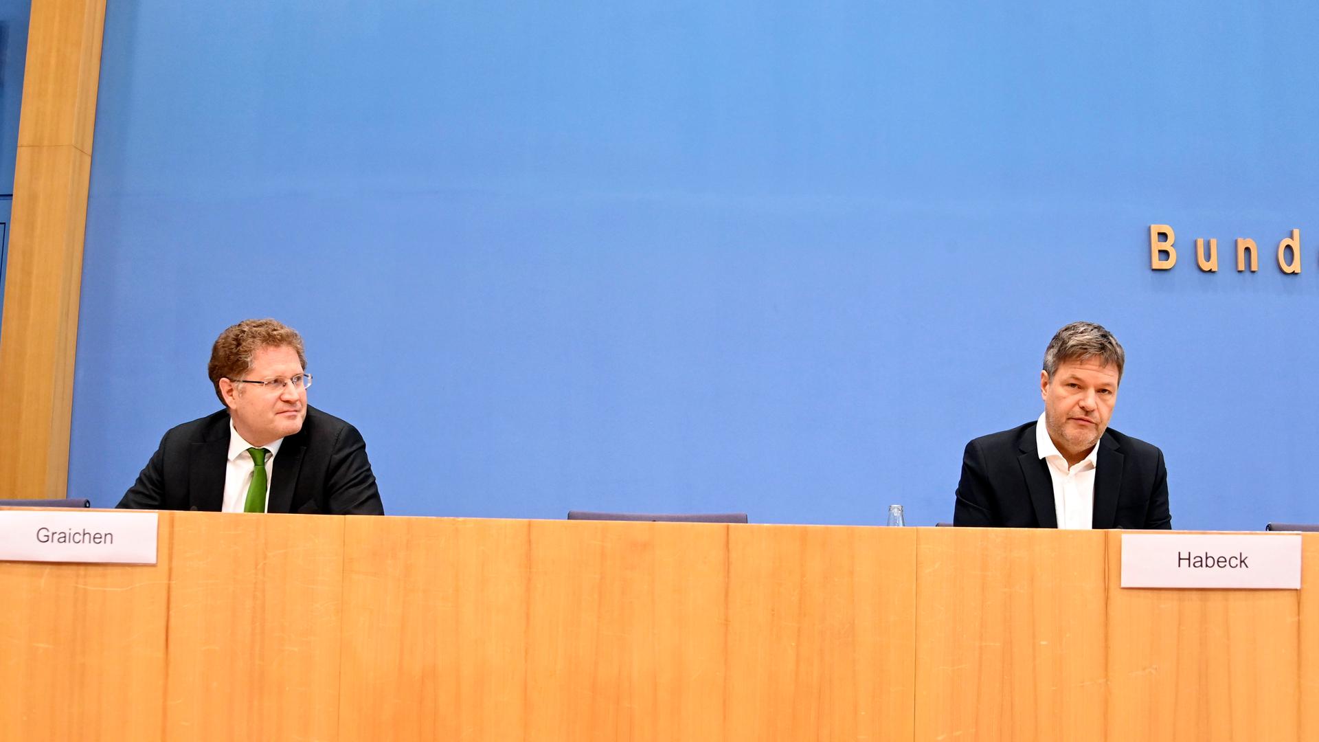 Patrick Graichen und Robert Habeck sitzen auf einem Podium an einem langen Tisch. Patrick Graichen und Robert Habeck sitzen auf einem Podium an einem langen Tisch.