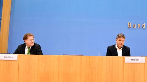 Patrick Graichen und Robert Habeck sitzen auf einem Podium an einem langen Tisch.