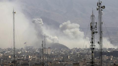 Über den Dächern von Teheran steigen Rauchwolken auf, im Vordergrund sind Sendemasten zu sehen.