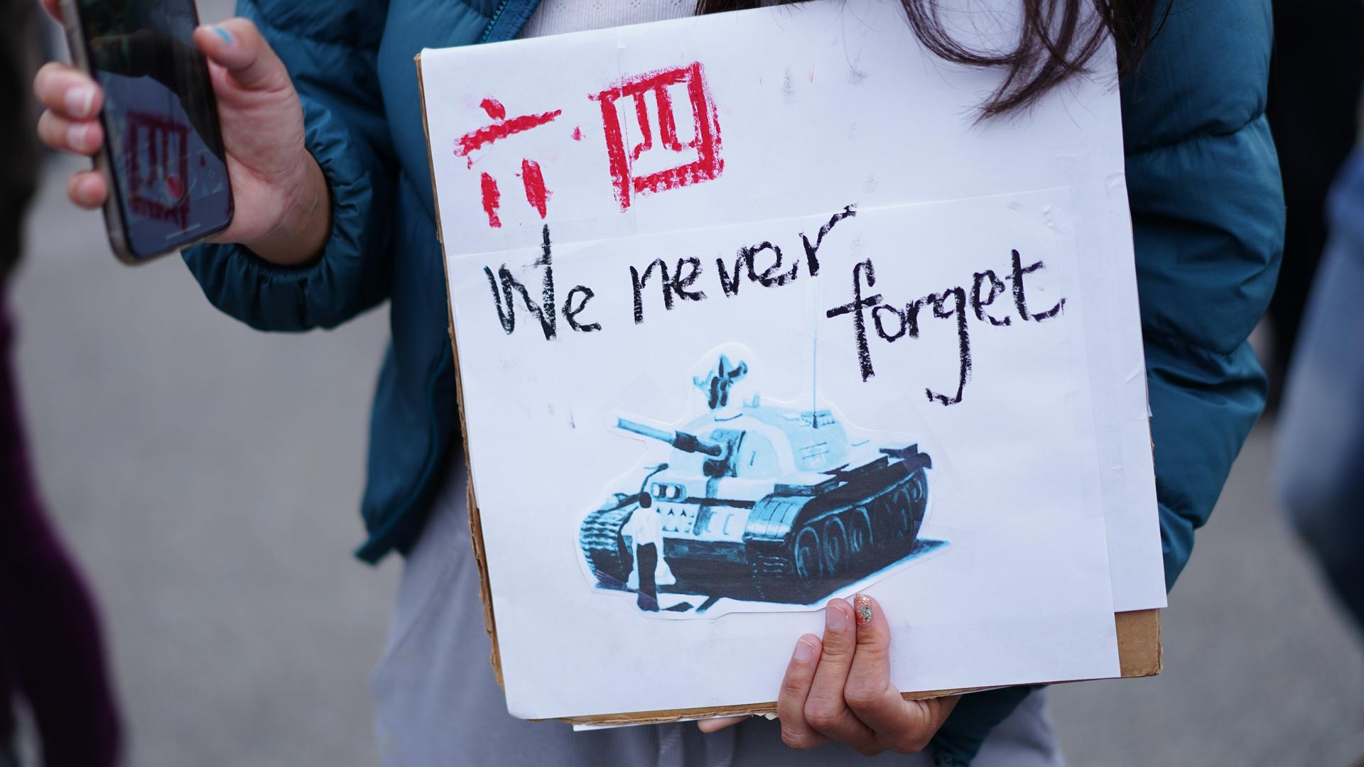 Bei einer Kundgebung zum Tiananmen-Massaker in San Francisco hält eine Demonstrierende ein Plakat mit der Aufschrift "We never forget" in den Händen.