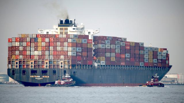 Ein Containerschiff mit einer großen Ladung und einem kleinen Beiboot.