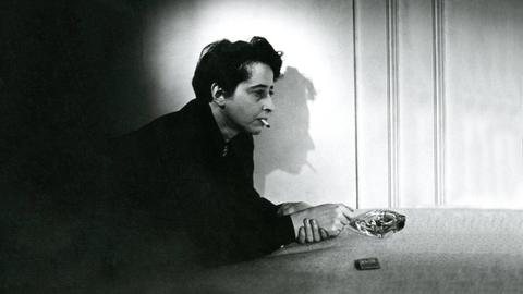 Filmstill aus "Hannah Arendt - Die Pflicht zum Ungehorsam" in dem Hannah Arendt Zigarette rauchend auf einem Tisch lehnt. Der Schatten ihres Profil ist an der Wand zu sehen. Filmstill aus "Hannah Arendt - Die Pflicht zum Ungehorsam" in dem Hannah Arendt Zigarette rauchend auf einem Tisch lehnt. Der Schatten ihres Profil ist an der Wand zu sehen.