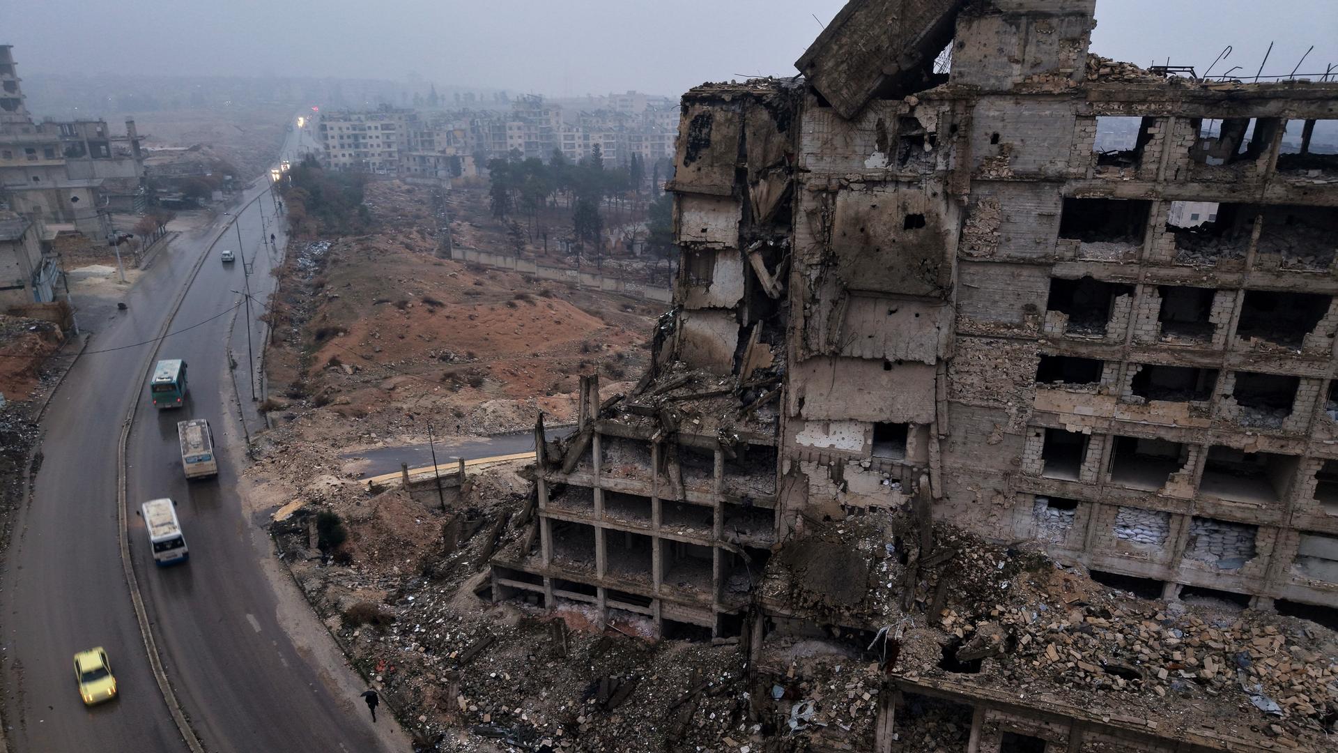 Busse mit vertriebenen Bewohnern fahren an einem zerstörten Gebäude vorbei, während sie in das Viertel Achrafieh zurückkehren.