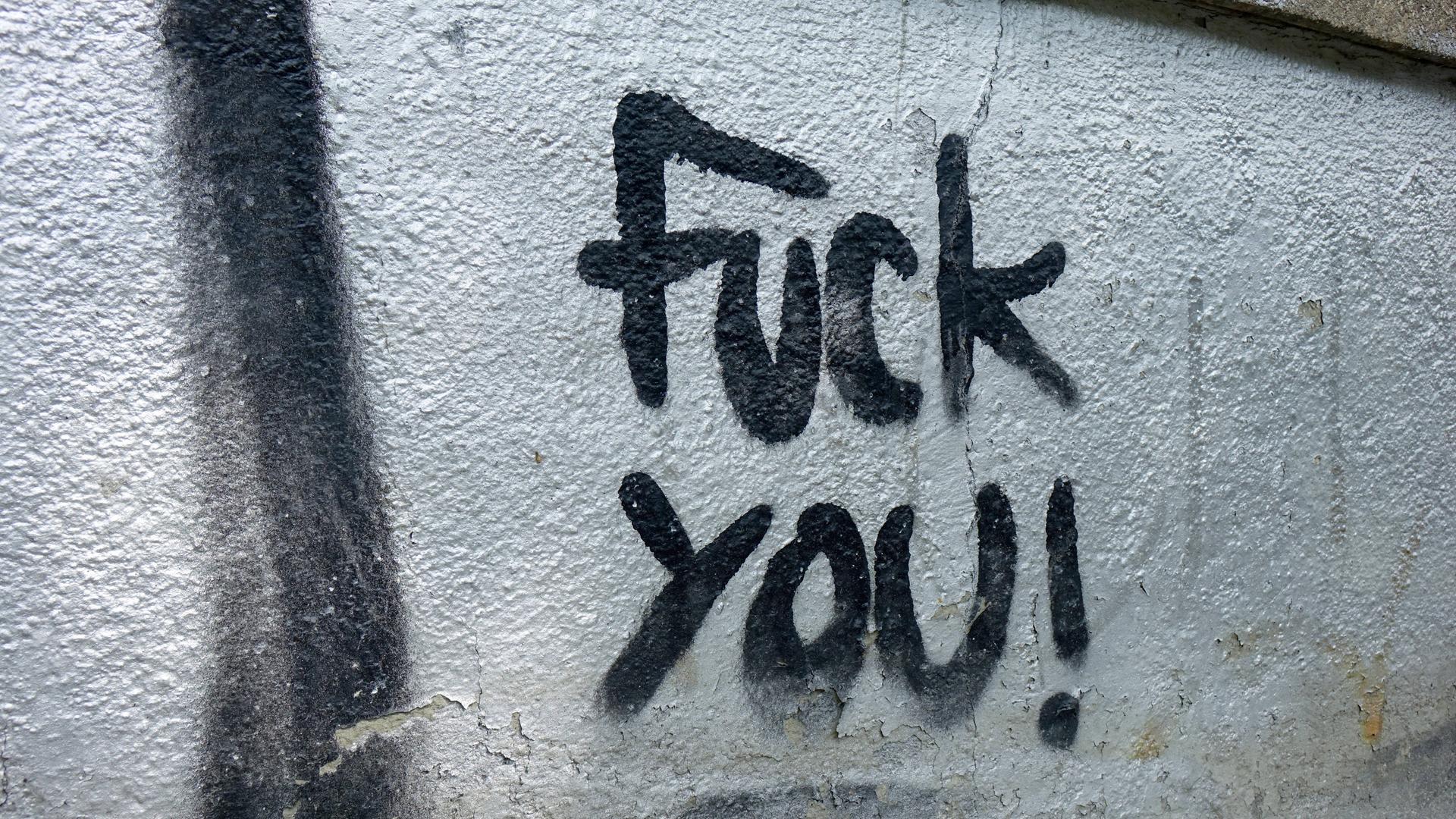 Schwarzer Schriftzug "Fuck you" auf einer Hauswand