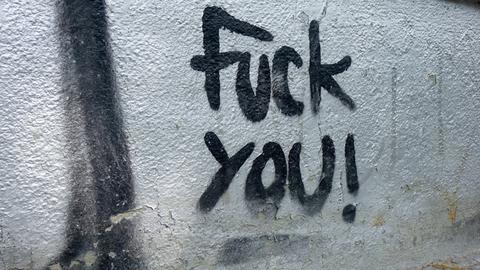 Schwarzer Schriftzug "Fuck you" auf einer Hauswand