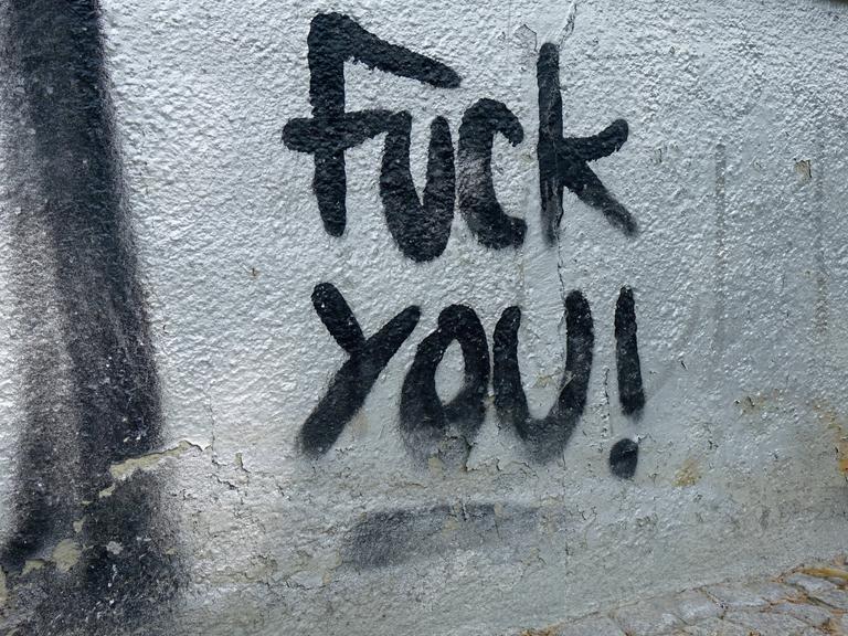 Schwarzer Schriftzug "Fuck you" auf einer Hauswand