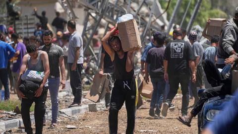 Palästinenser tragen Kisten und Taschen mit Lebensmitteln und humanitären Hilfspaketen, die von der Gaza Humanitarian Foundation, einer von Israel anerkannten und von den USA unterstützten Organisation geliefert wurden.