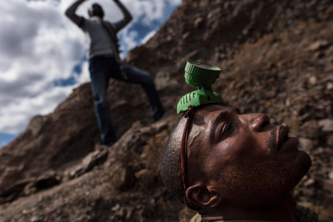 Ein Minenarbeiter mit einer Stirnlampe auf dem Kopf beim Einstieg in eine Kupfer- und Kobaltmine in Kawama / Kongo.