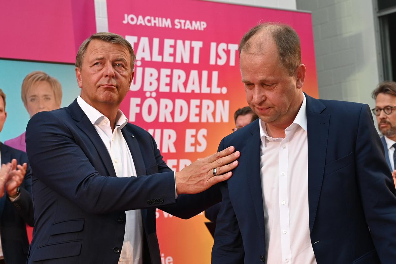 Der FDP-Spitzenkandidat für die Landtagswahl in Nordrhein-Westfalen, Joachim Stamp (r), steht bei der Wahlparty seiner Partei auf der Bühne und wird von Christof Rasche, Vorsitzender der FDP-Landtagsfraktion NRW, getröstet