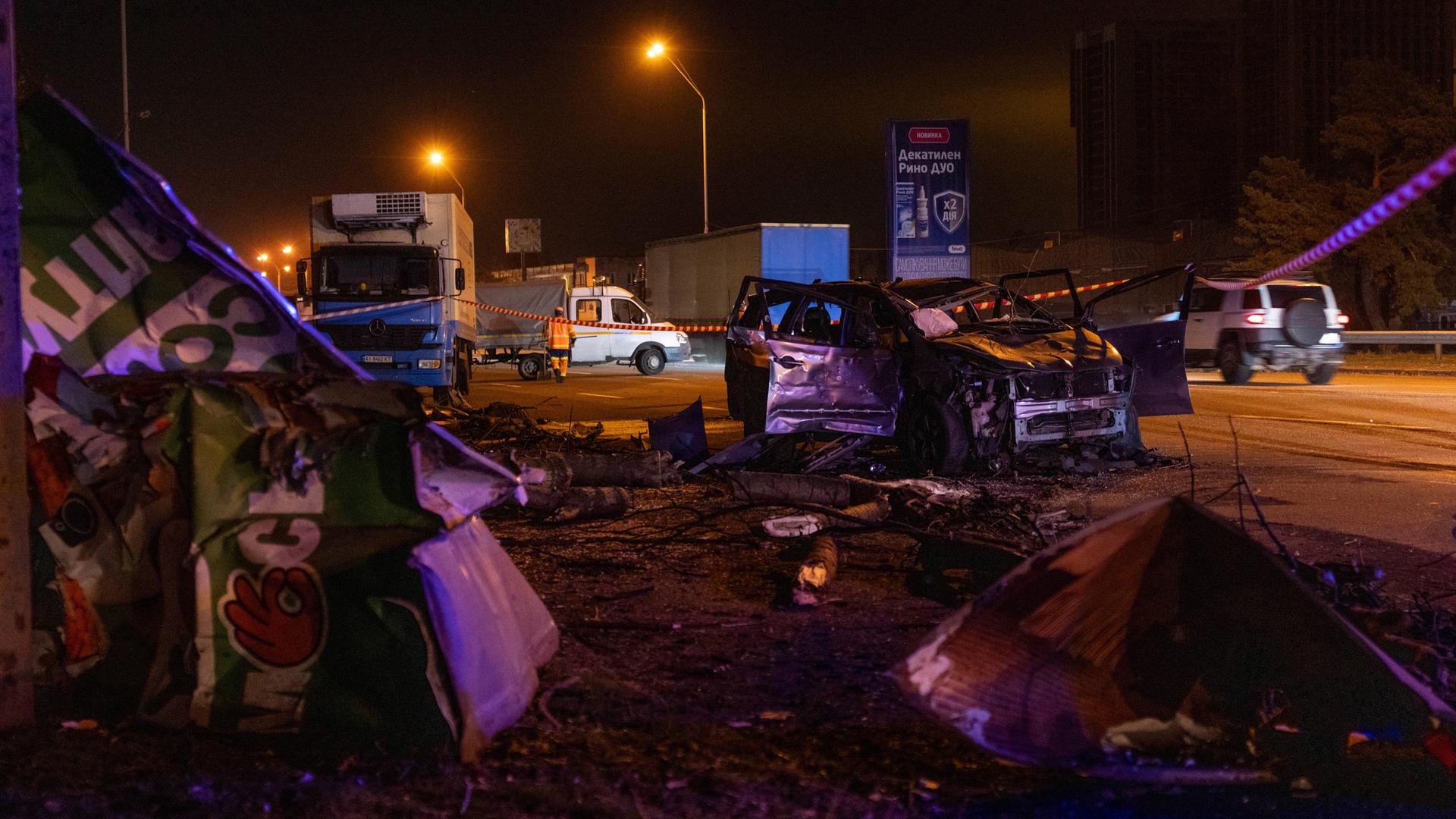 Eine Straße in Kiew, auf der mehrere zerstörte Autos und Lkw stehen.