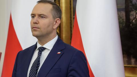 Der polnische Präsident Karol Nawrocki steht vor der polnischen Flagge und blickt ernst in die Ferne.