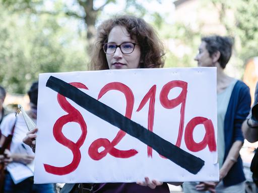 Protest gegen den Abtreibungsparagraf in Berlin, eine Frau hält ein Schild mit dem durchgestrichenen Pararafen 219a in der Hand.