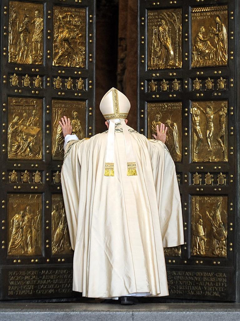 Papst Franziskus in weißem Gewand in der Rückansicht vor der Heiligen Pforte des Petersdoms im Vatikan, 8. Dezember 2015