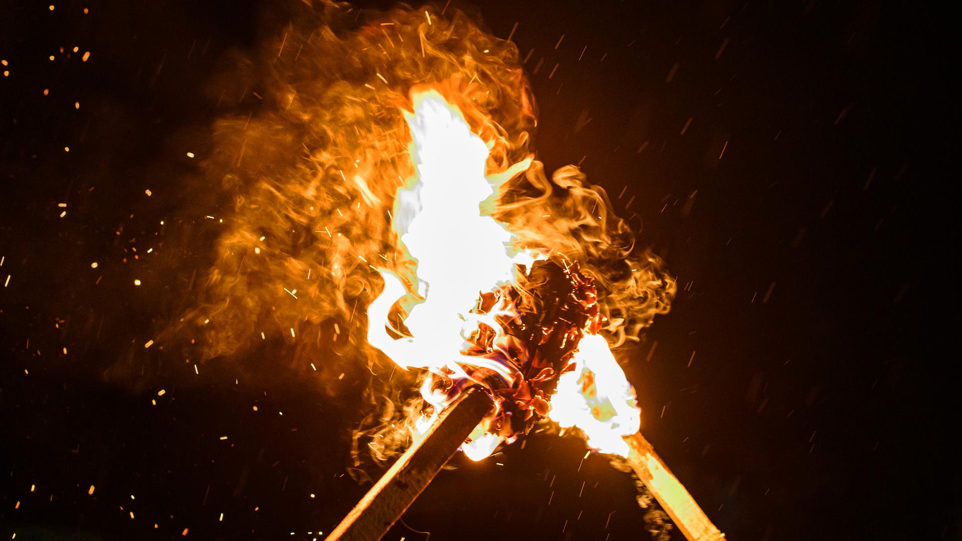 Zwei aneinanderstoßende, brennende Fackeln in der Nacht. Zwei aneinanderstoßende, brennende Fackeln in der Nacht.