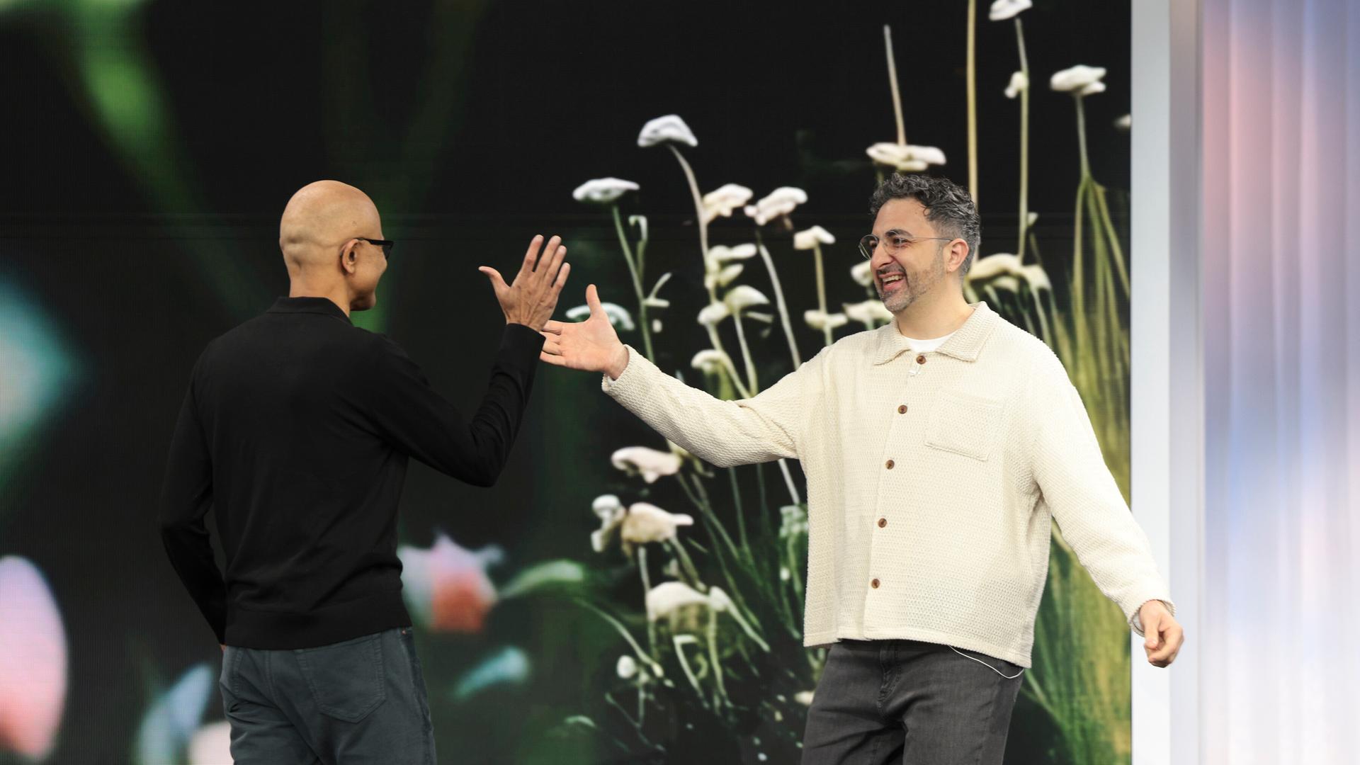 Satya Nadella, Microsoft-Chef, heißt Mustafa Suleyman, KI-Chef bei Microsoft, bei einer Präsentation auf einer Bühne willkommen. 