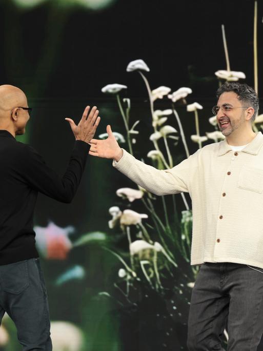 Satya Nadella, Microsoft-Chef, heißt Mustafa Suleyman, KI-Chef bei Microsoft, bei einer Präsentation auf einer Bühne willkommen. 