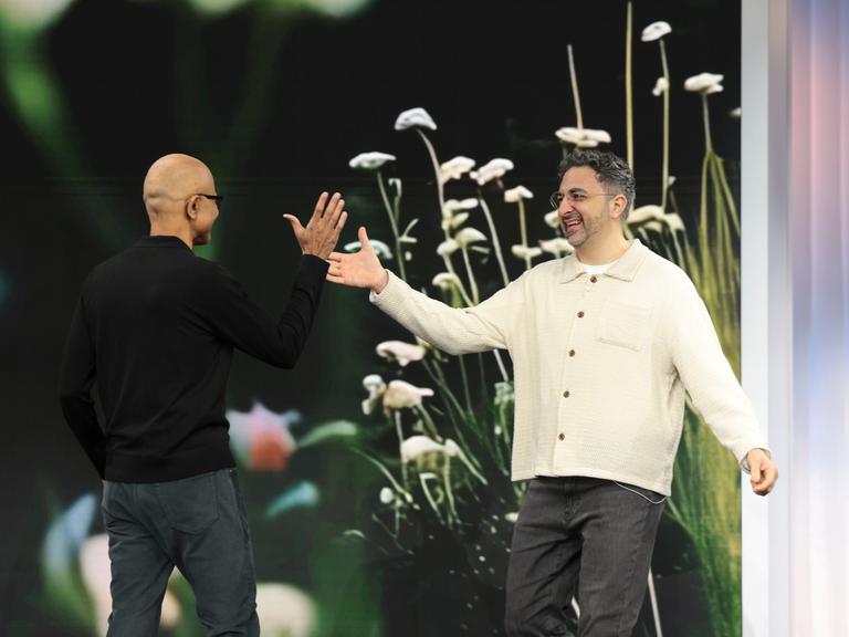 Satya Nadella, Microsoft-Chef, heißt Mustafa Suleyman, KI-Chef bei Microsoft, bei einer Präsentation auf einer Bühne willkommen. 