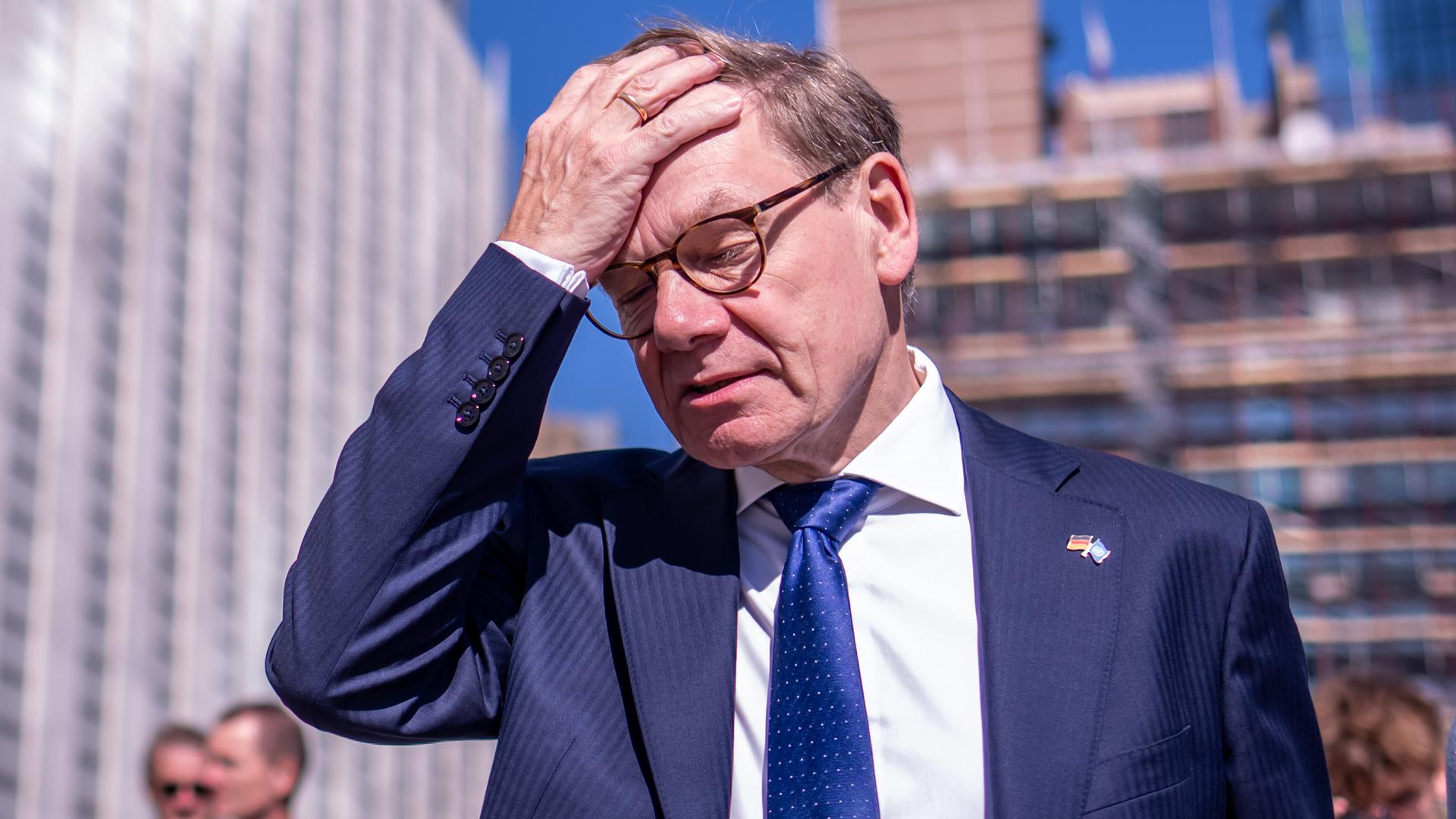Ein Mann trägt einen dunkelblauen Anzug. Er greift sich mit der rechten Hand an die Stirn und wirkt dabei genervt. Es ist der deutsche Außenminister Johann Wadephul von der CDU. 