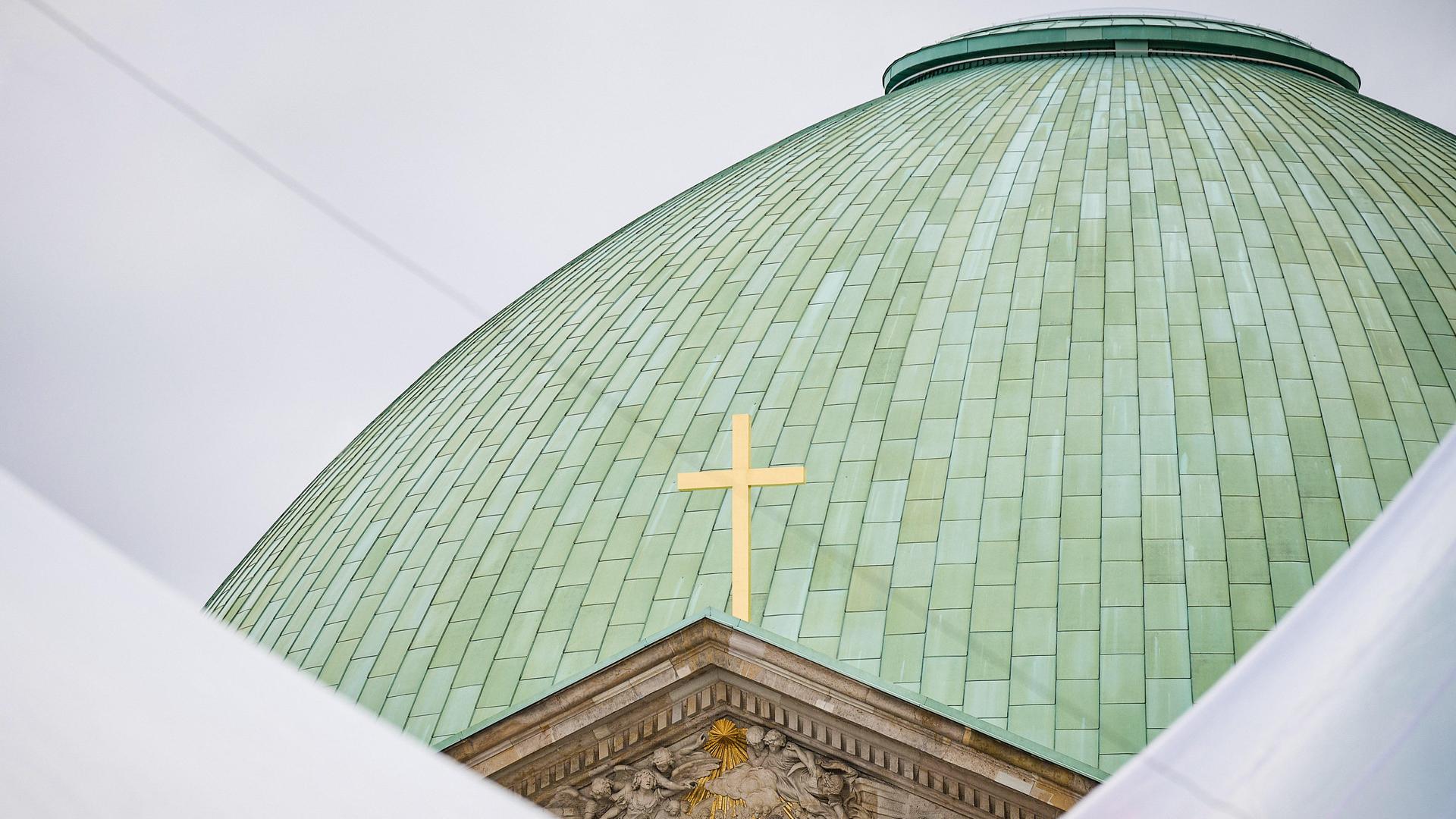 Die grüne Kuppel der  Berliner Sankt Hedwigs-Kathedrale mit einem Kreuz. 