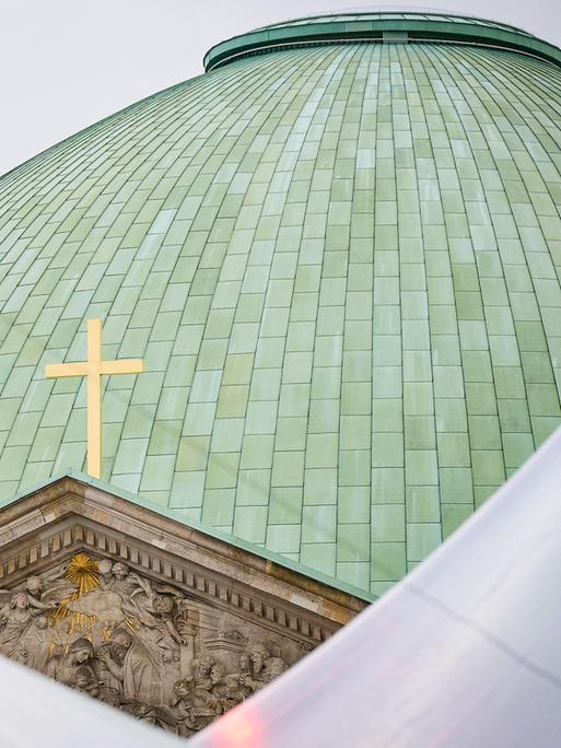 Die grüne Kuppel der  Berliner Sankt Hedwigs-Kathedrale mit einem Kreuz. 