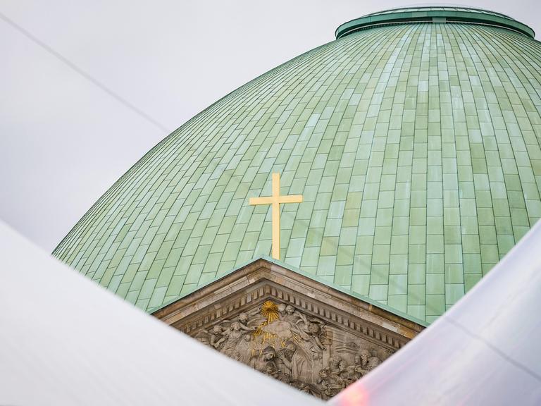 Die grüne Kuppel der  Berliner Sankt Hedwigs-Kathedrale mit einem Kreuz. 