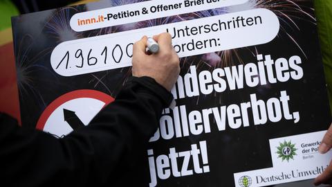 Ein Mann trägt auf ein Plakat mit der Aufschrift "Bundesweites Böllerverbot, jetzt!" die Anzahl der Unterzeichnenden der Petition ein