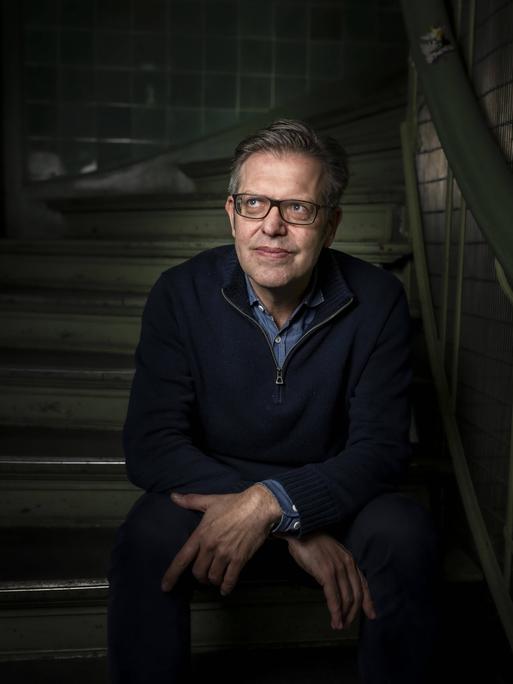 Steffen Mau, Soziologe für Makrosoziologie am Institut für Sozialwissenschaften der Humboldt-Universität zu Berlin, HU sitzt auf einer Treppe.