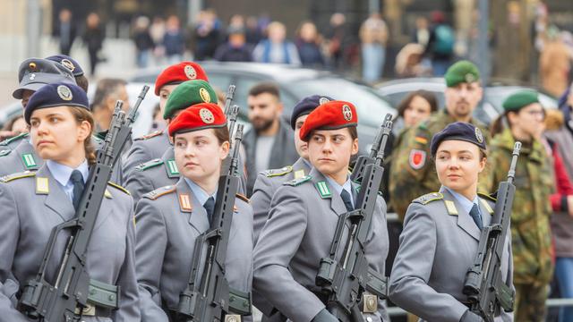 Junge Soldatinnen und Soldaten gehen während einer Parade nebeneinander her.