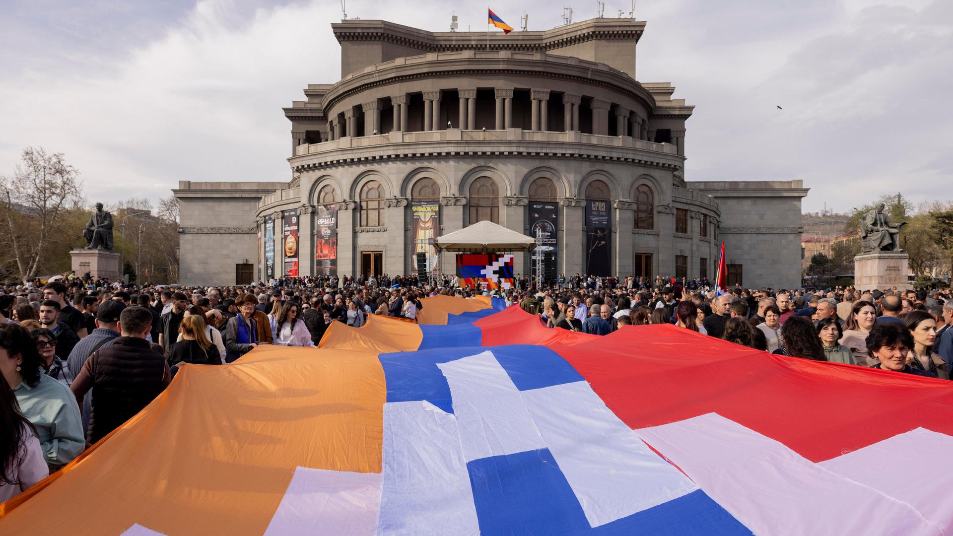 Menschen tragen eine große Flagge der Republik Arzach während einer Demonstration vor der Nationaloper in Yerevan. Menschen tragen eine große Flagge der Republik Arzach während einer Demonstration vor der Nationaloper in Yerevan.