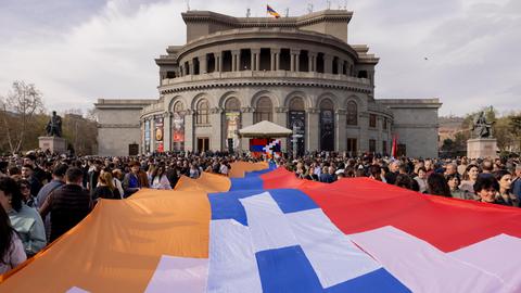 Menschen tragen eine große Flagge der Republik Arzach während einer Demonstration vor der Nationaloper in Yerevan.