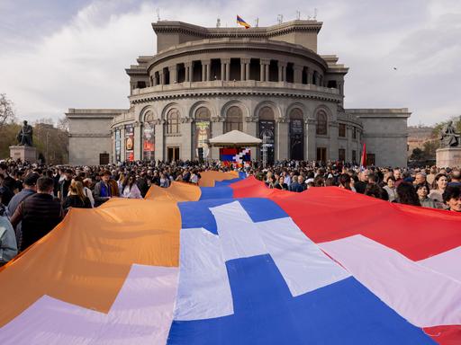 Menschen tragen eine große Flagge der Republik Arzach während einer Demonstration vor der Nationaloper in Yerevan. Menschen tragen eine große Flagge der Republik Arzach während einer Demonstration vor der Nationaloper in Yerevan.