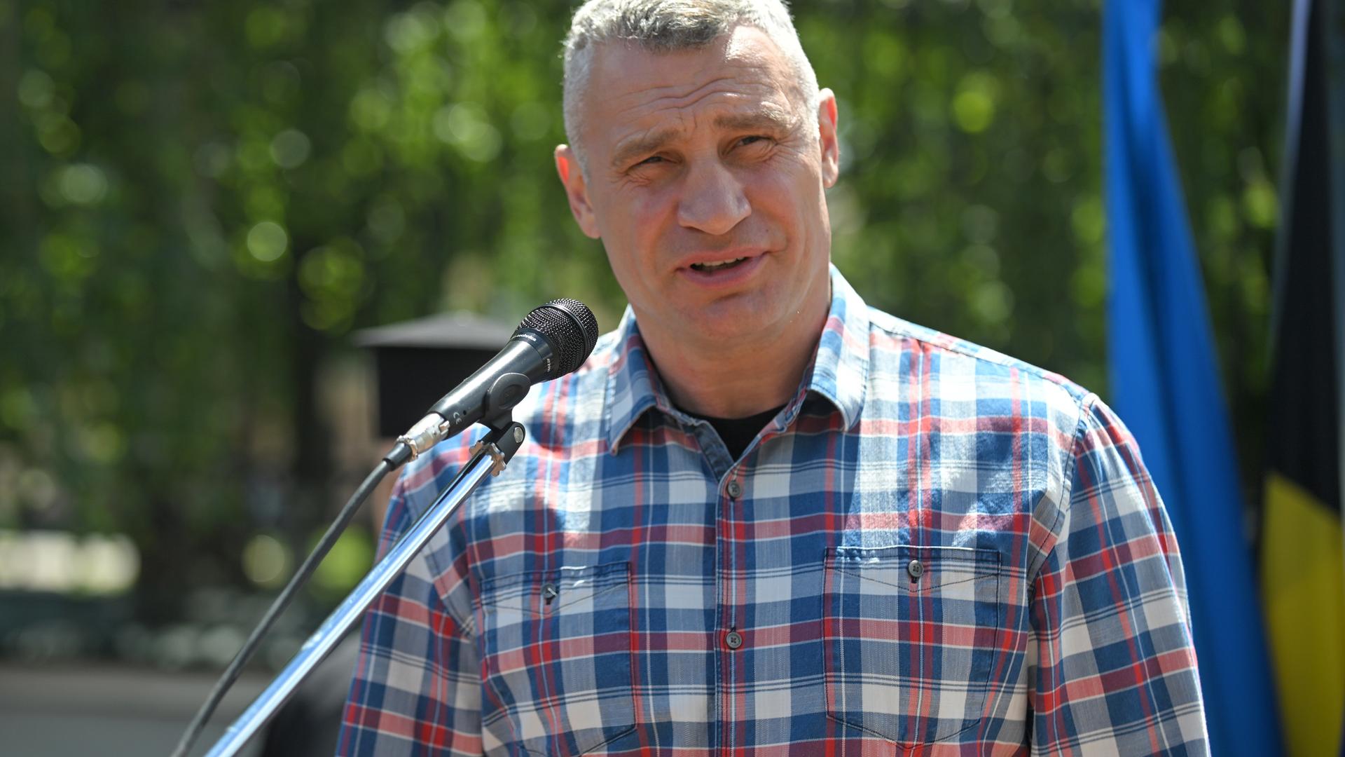 Der Bürgermeister der ukrainischen Hauptstadt Kiew, Vitali Klitschko, spricht in ein Mikrofon. Er trägt ein kariertes Hemd.