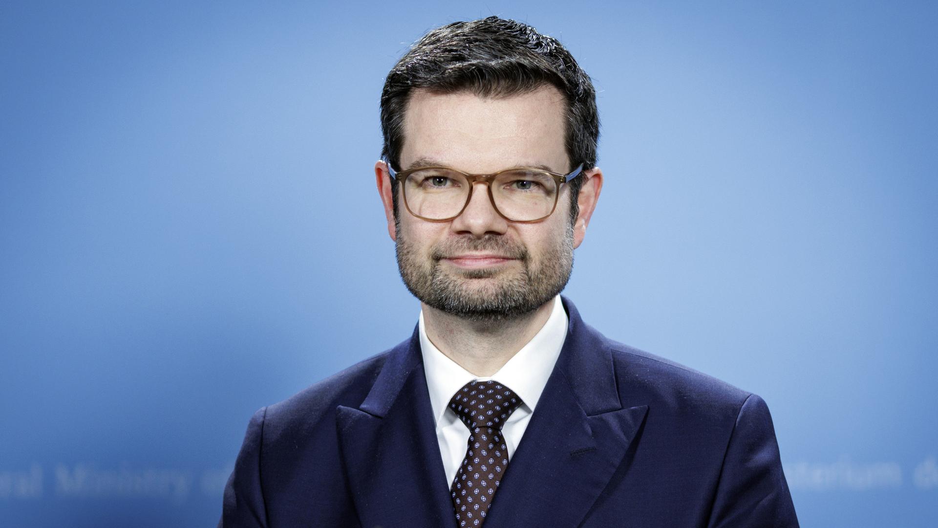 Porträt von Marco Buschmann. Der Minister trägt Anzug, Brille und Drei-Tage-Bart.