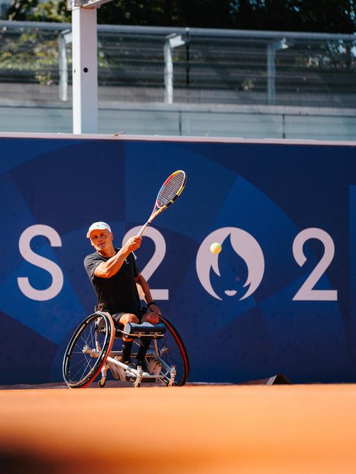 Ein Rollstuhltennissspieler schlägt einen Ball von der Grundlinie beim Training auf dem Paralympicsgelände in Paris.