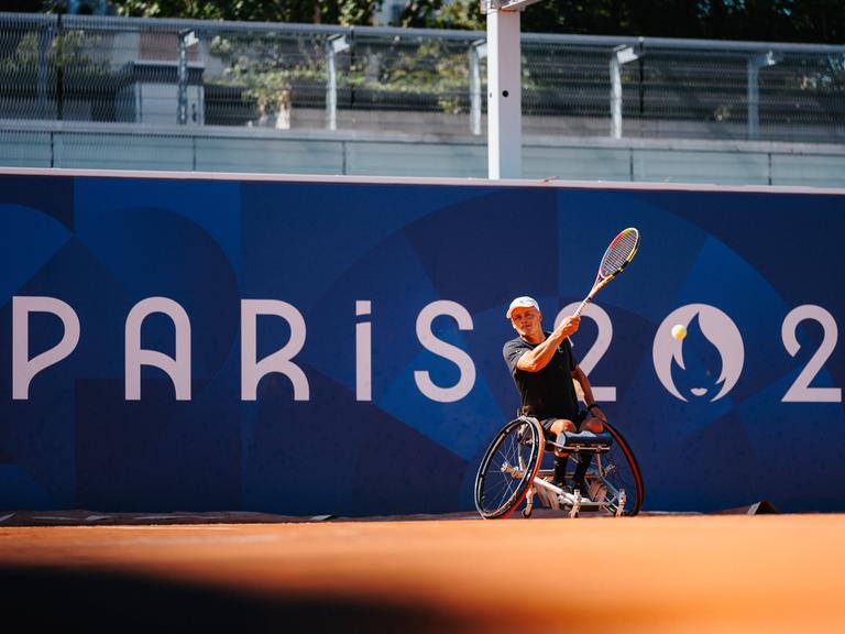 Ein Rollstuhltennissspieler schlägt einen Ball von der Grundlinie beim Training auf dem Paralympicsgelände in Paris.