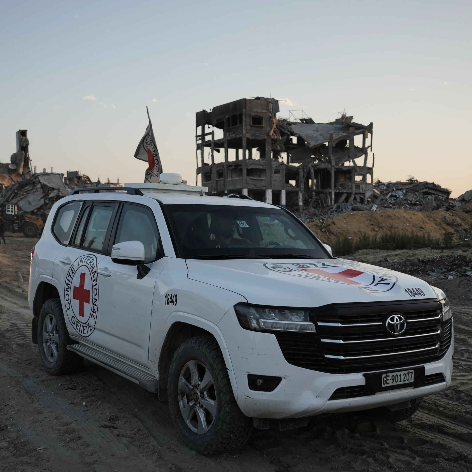 Ein Geländewagen des Roten Kreuzes fährt durch die Ruinenlandschaft des Gazastreifens.
