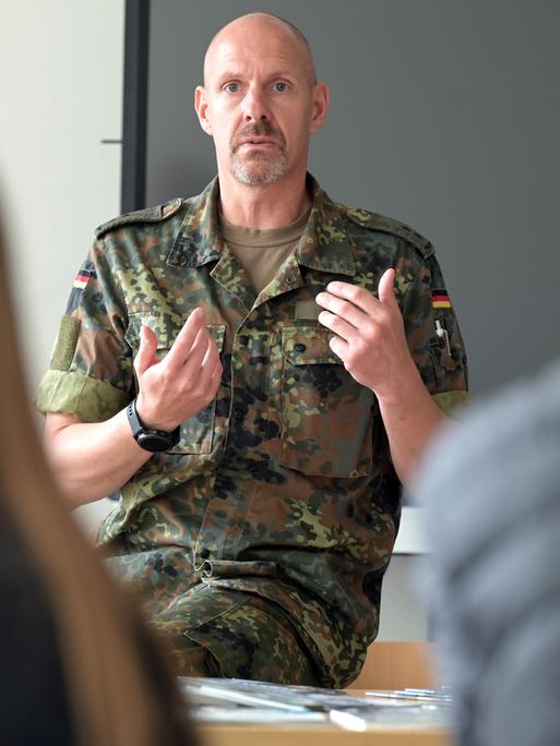 Bundeswehr-Offizier spricht vor einer Gymnasialklasse.