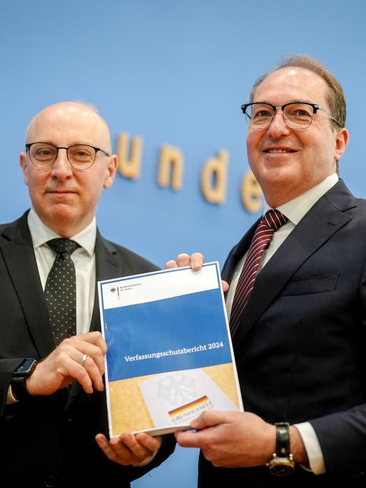 Alexander Dobrindt und Sinan Selenhalten halten gemeinsam den Verfassungsschutzbericht 2024 in die Kamera.