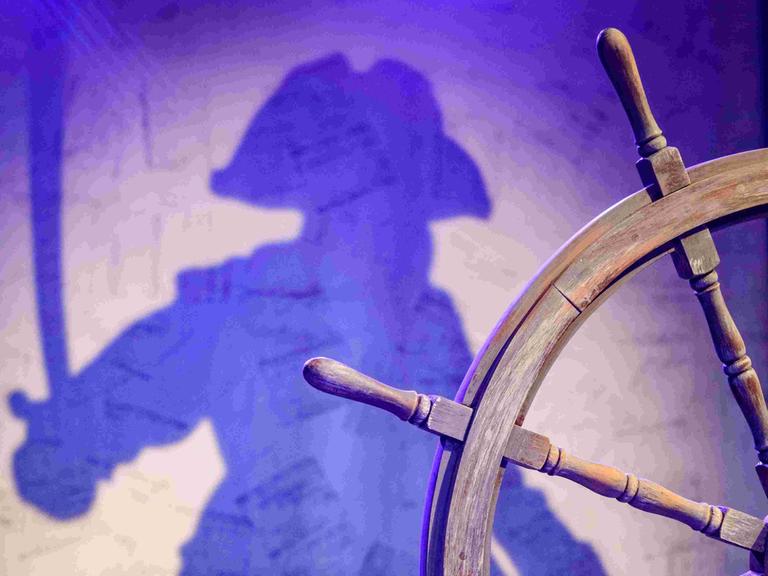 Ein Steuerrad und der Schatten eines Piraten - bei einer Probe für das Stück "Johnny Hübner greift ein" des jungen Theaters Nordhausen am 20. Oktober 2022 in Nordhausen (Thüringen).
