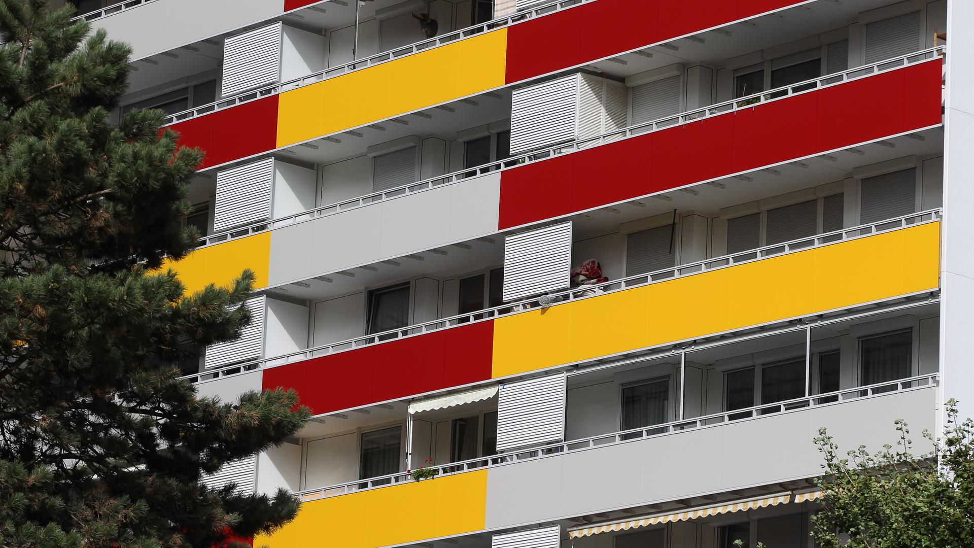 Hausfassade eines Mehrfamilienhausees mit gelber und roter Verkleidung an den Balkonen.