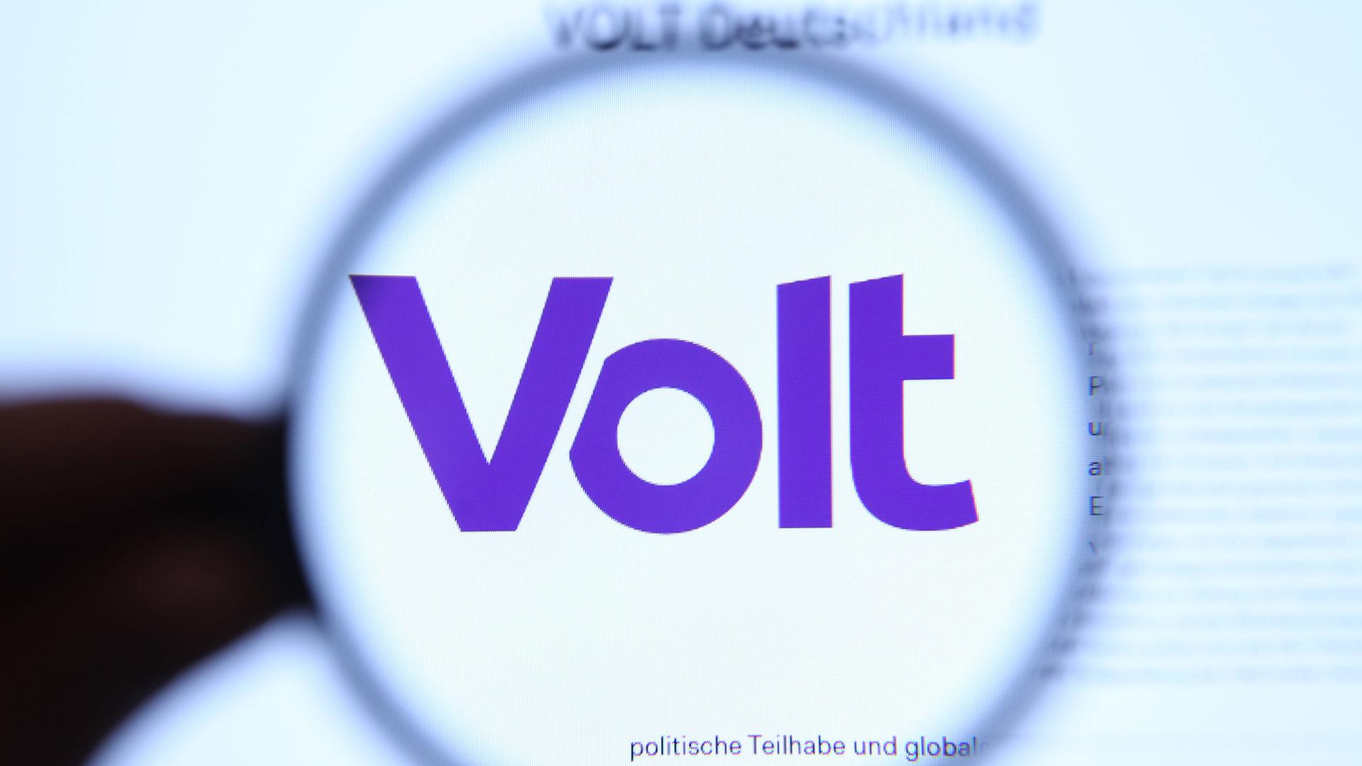 Ein Lupe vergrößert den Namen Volt für ein Symbolbild der Partei.