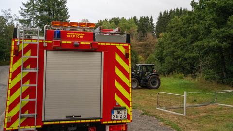 Ein Feuerwehrauto auf einer Waldstraße in Monschau. Im Hintergrund ein Bagger und ein umgekipptes Fußballtor.
